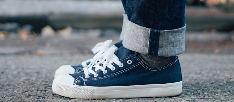 Jean replié sur des baskets en toile bleues