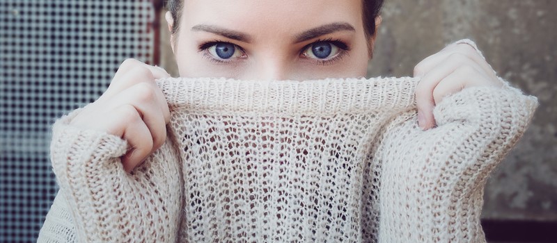 Femme se cachant le visage derrière un pull tricoté large