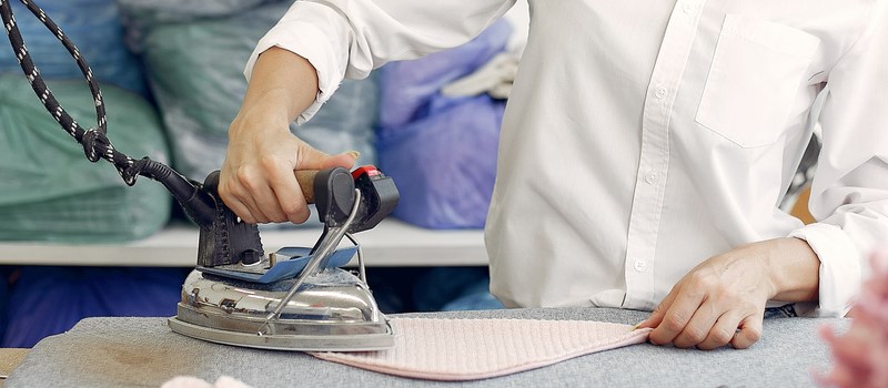 Femme en train de repasser sur une presse professionnelle